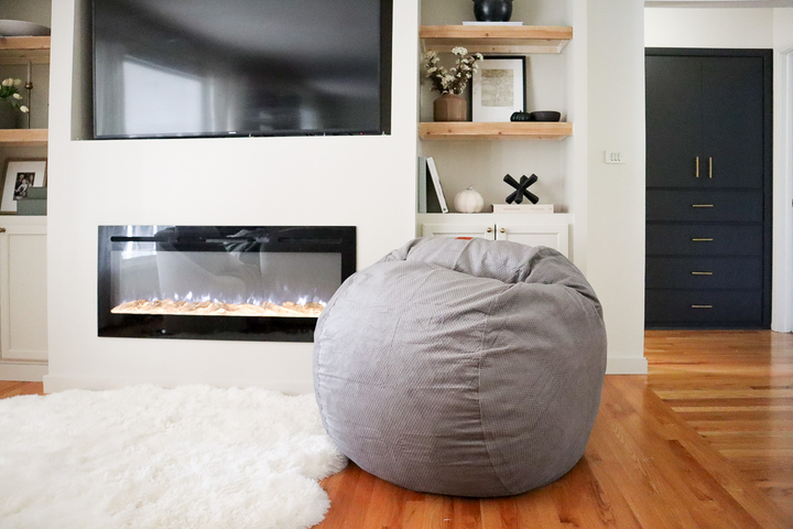 A bean bag chair in a living room in front of a fire place. 