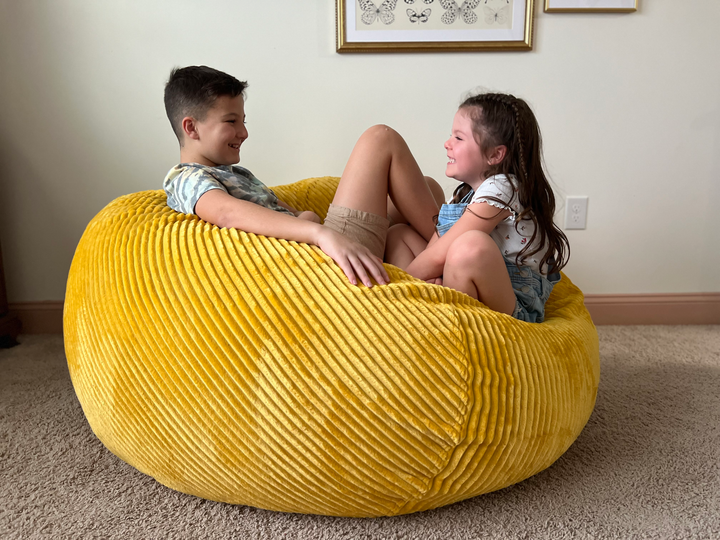 Two children sitting on a CordaRoy's bean bag.