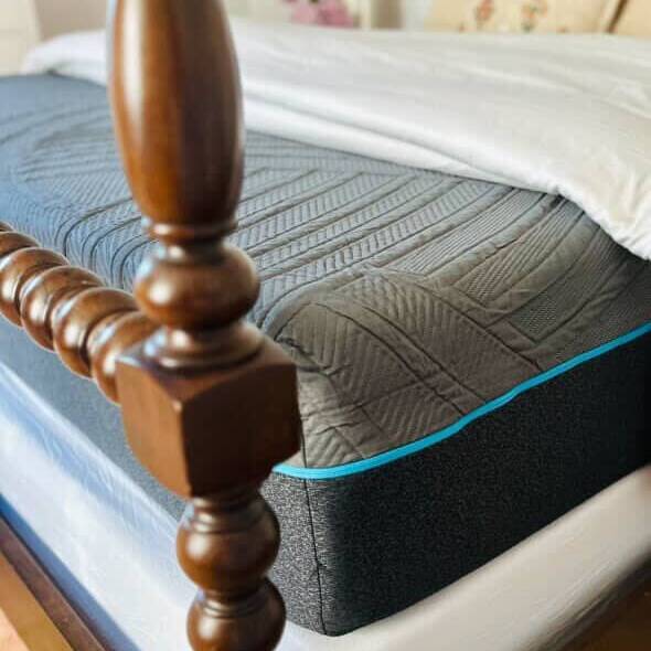 Gray mattress topper on a bed with wooden footboard