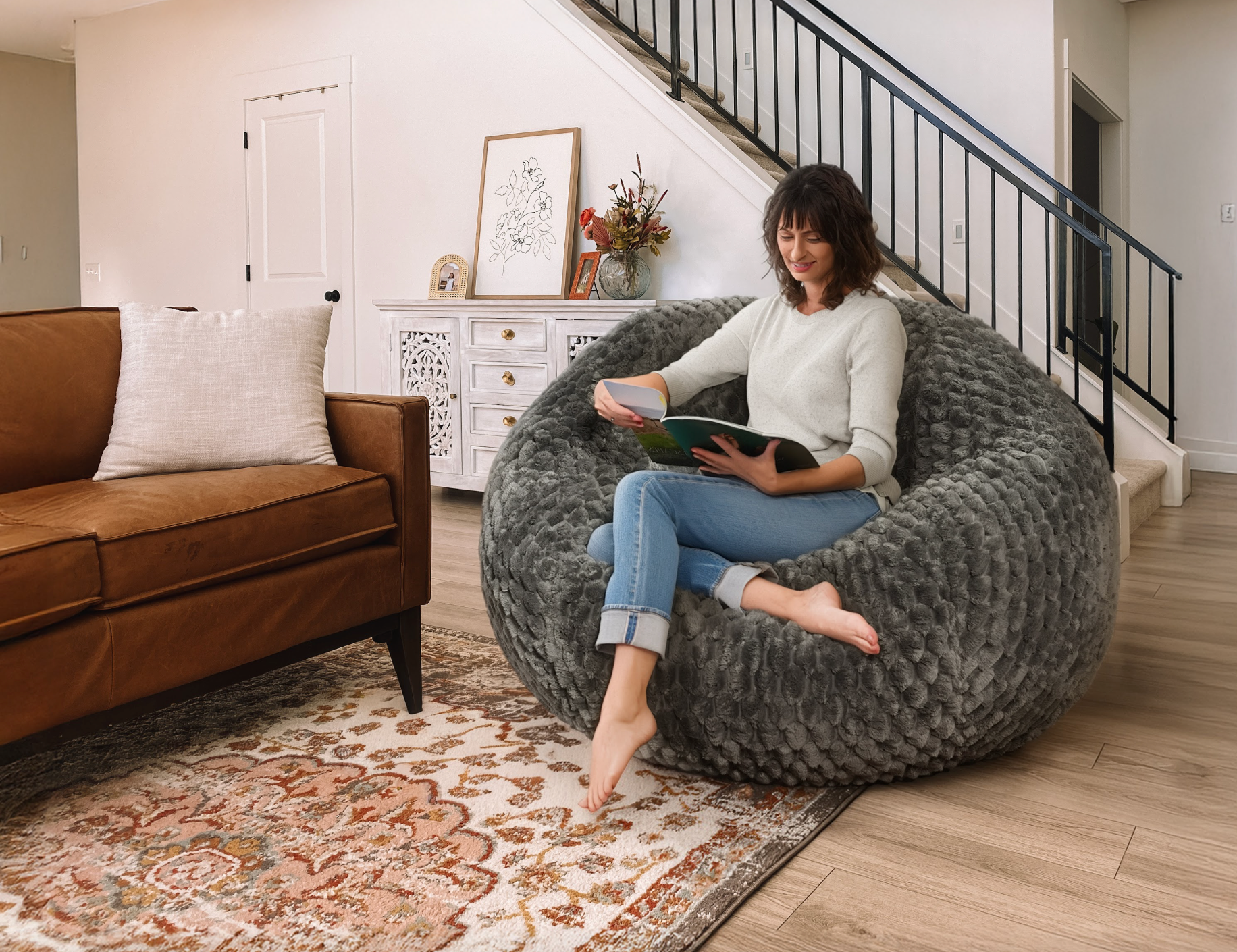 A woman reads on a bean bag chair in her living room.
