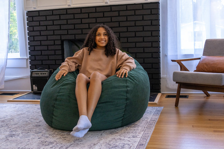 A teenager sitting in a bean bag chair in a living room.