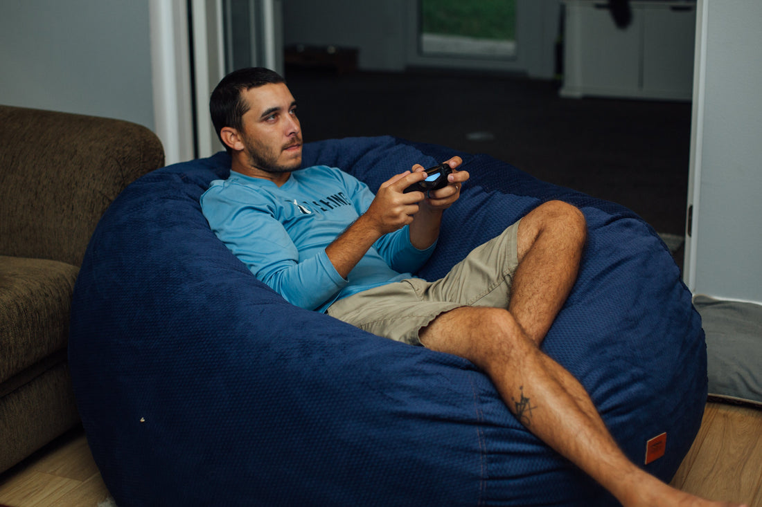 A man gaming in a bean bag chair. 