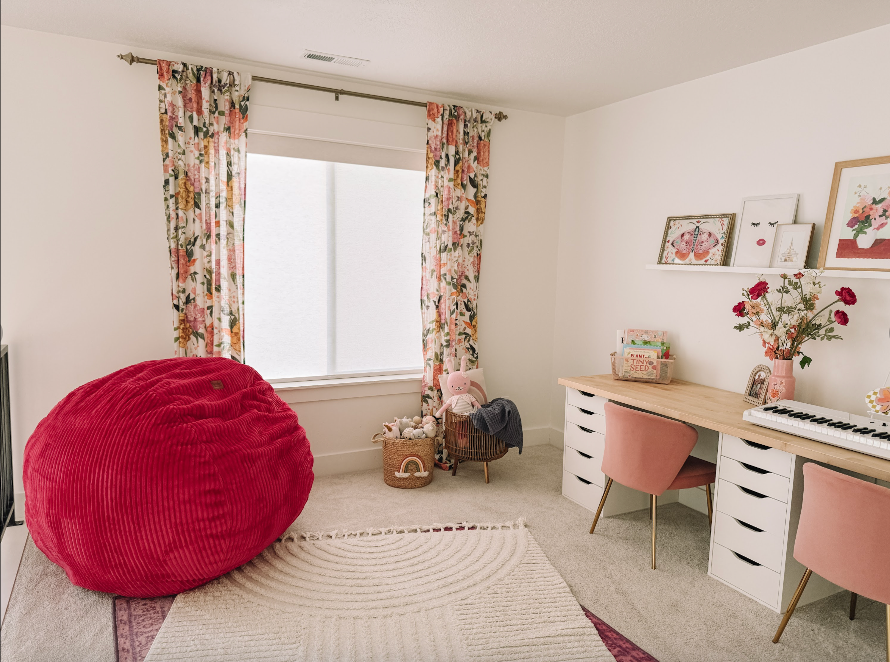 A girls room with a desk, rug, curtains, and a red bean bag chair.