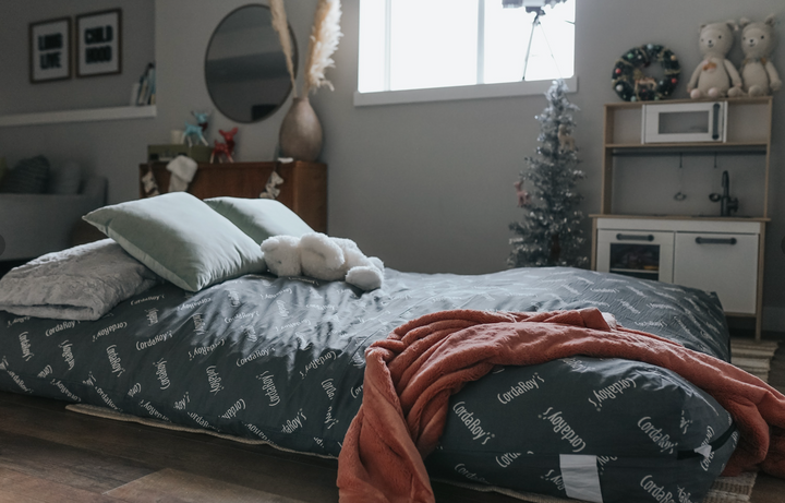 A CordaRoy's Bean Bag Chair made into a bed with a Christmas tree in the background. 