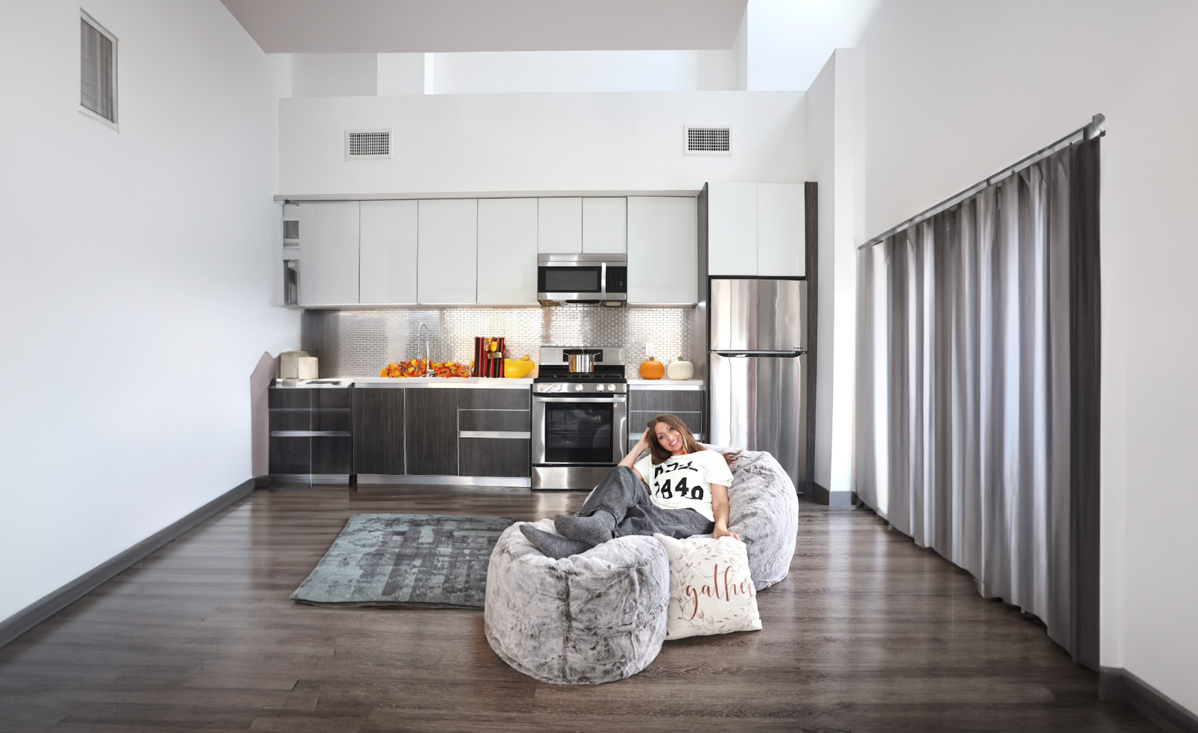 A cordaroys bean bag chair in the center of a room that features a kitchen. 