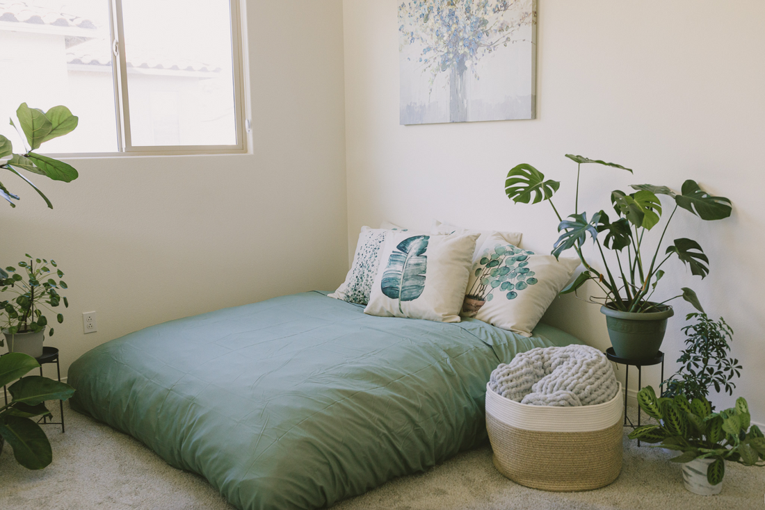 A cordaroys bean bag in mattress form layered with blankets and pillows. 