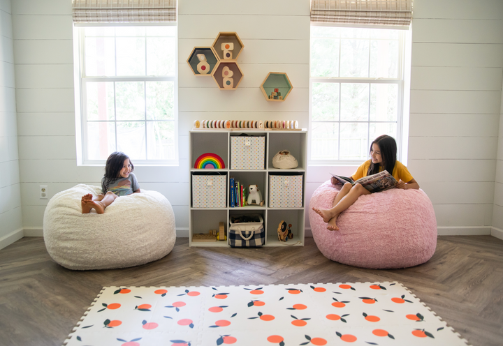 Two girls sitting on CordaRoy bean bags in a playroom. 