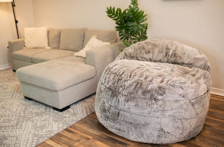 A CordaRoy's bean bag chair next to a couch in a living room. 