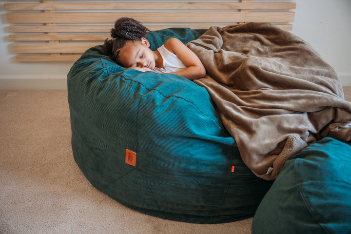A girl sleeps on a comfortable CordaRoy's bean bag chair. 