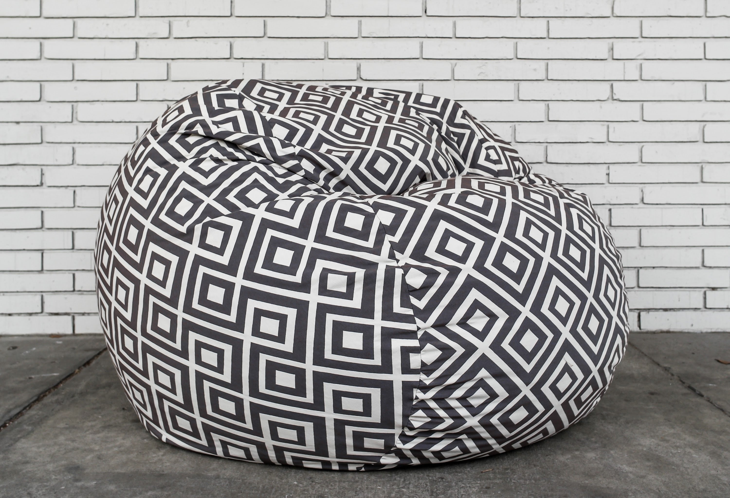 A stylish CordaRoy's bean bag chair against a brick wall.