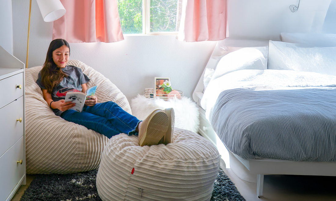 A teen sits on a cordaroys bean bag in her bedroom