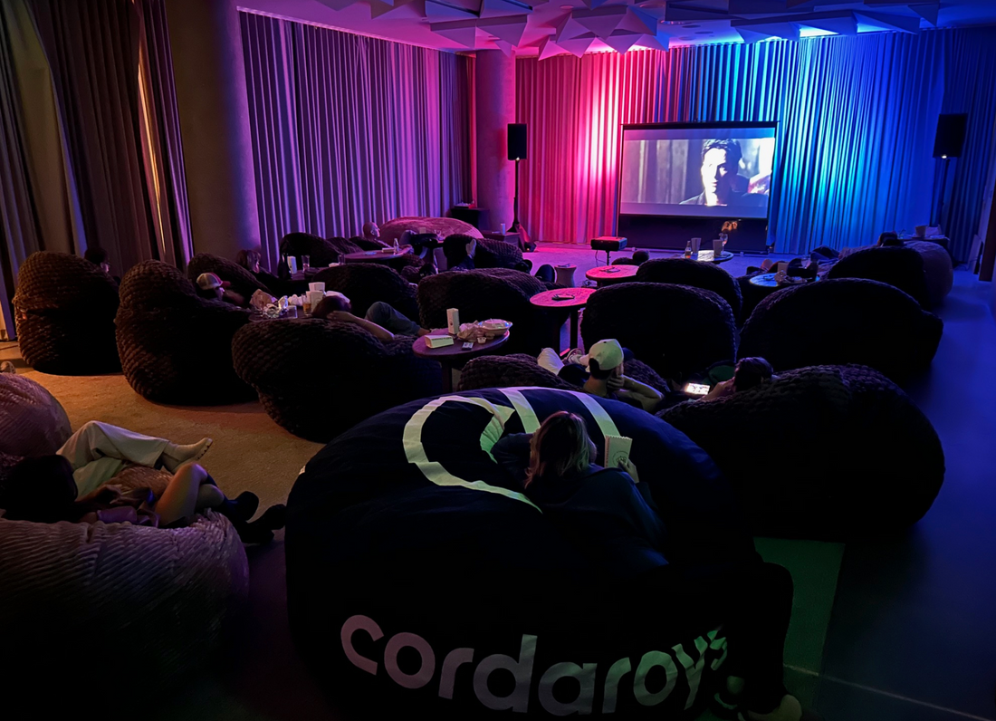 People sitting in cordaroys bean bags in a dark movie room.