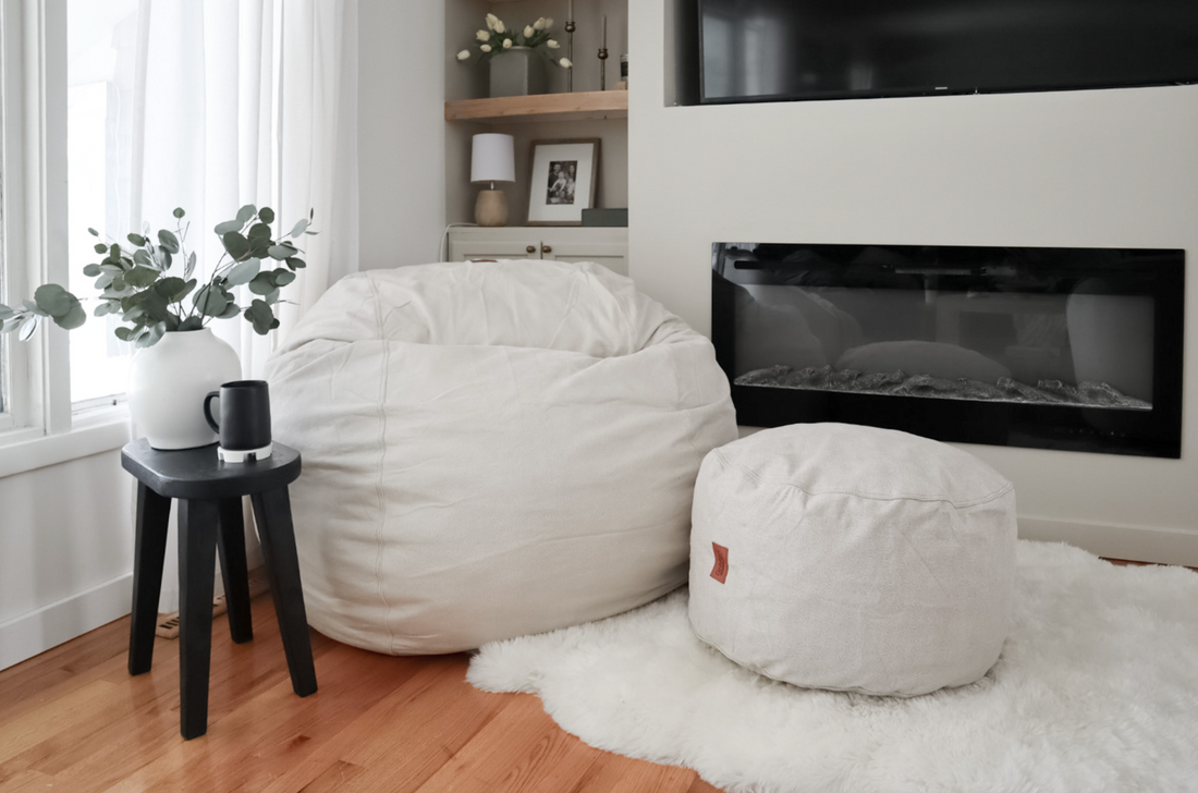 A white cordaroys bean bag and footstool near a fireplace.