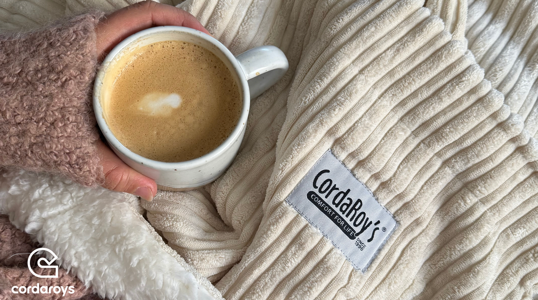 A person holds a cup of coffee over a cordaroys chair cover. 