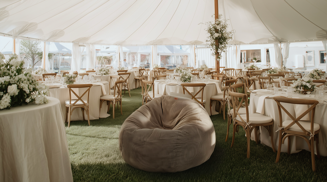 A cordaroys bean bag is placed under a tent at an outdoor wedding.