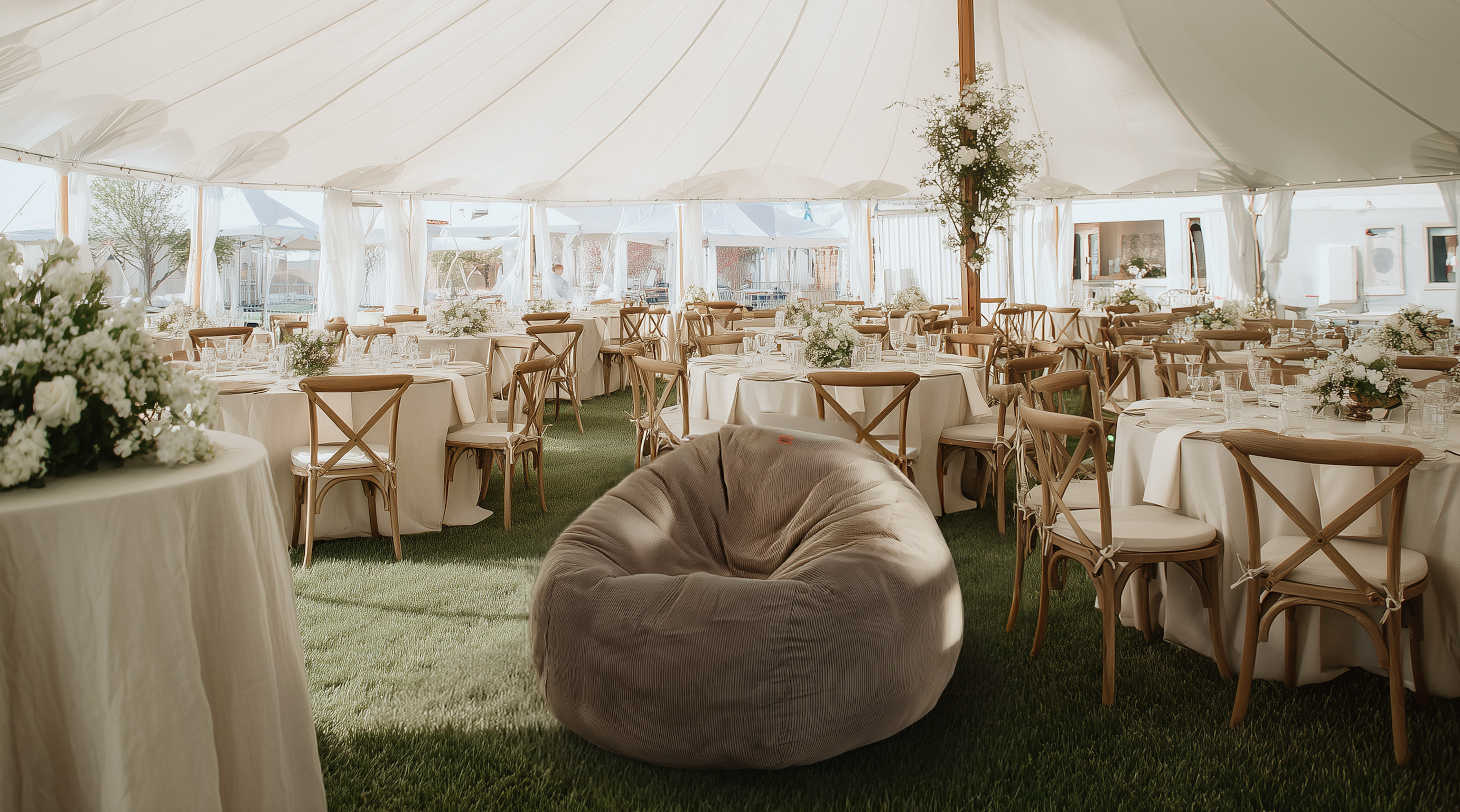 A cordaroys bean bag is placed under a tent at an outdoor wedding.