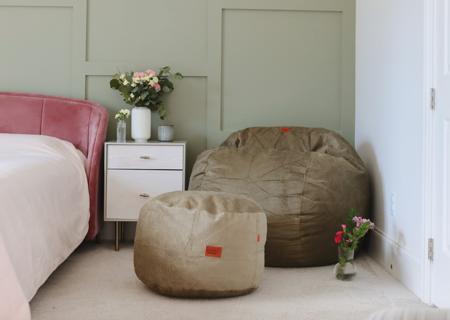 A cordaroys bean bag chair and pouf in the corner of a bedroom. 
