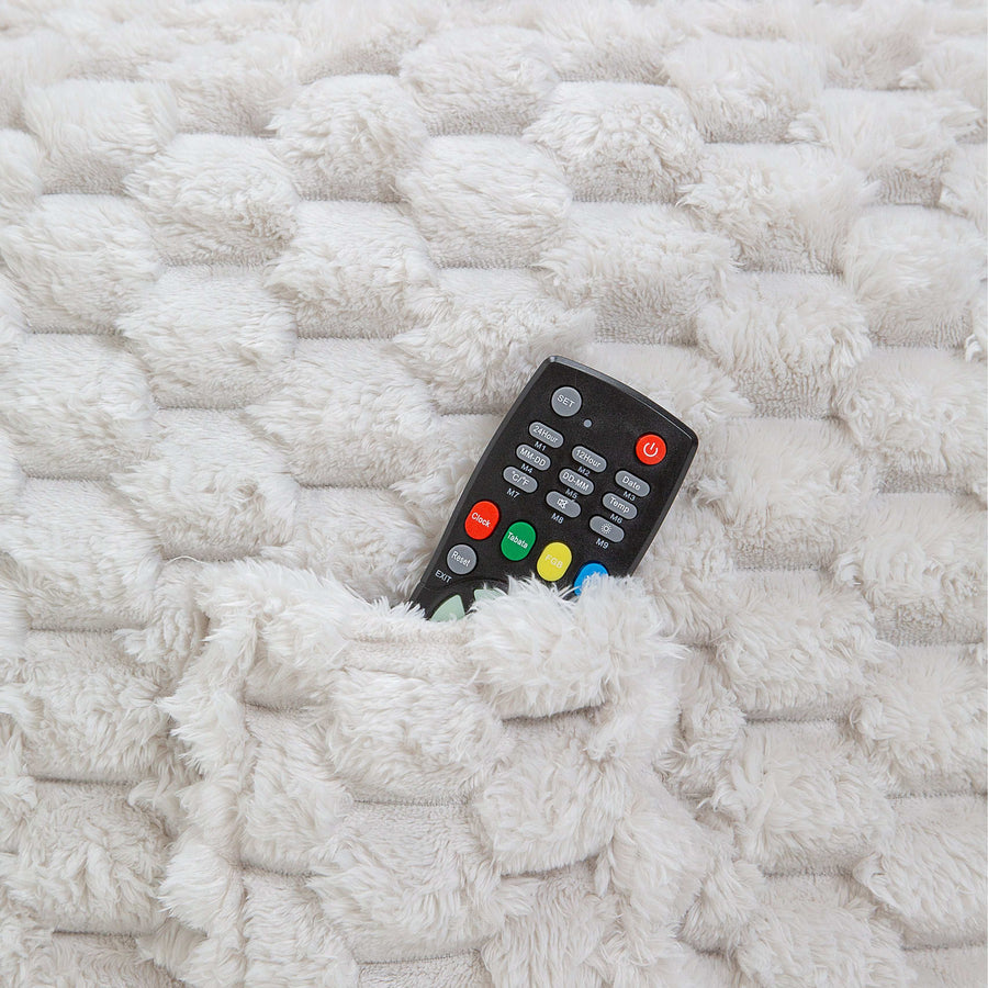 Black remote control with colorful buttons inside a bean bag pocket on a textured white surface
