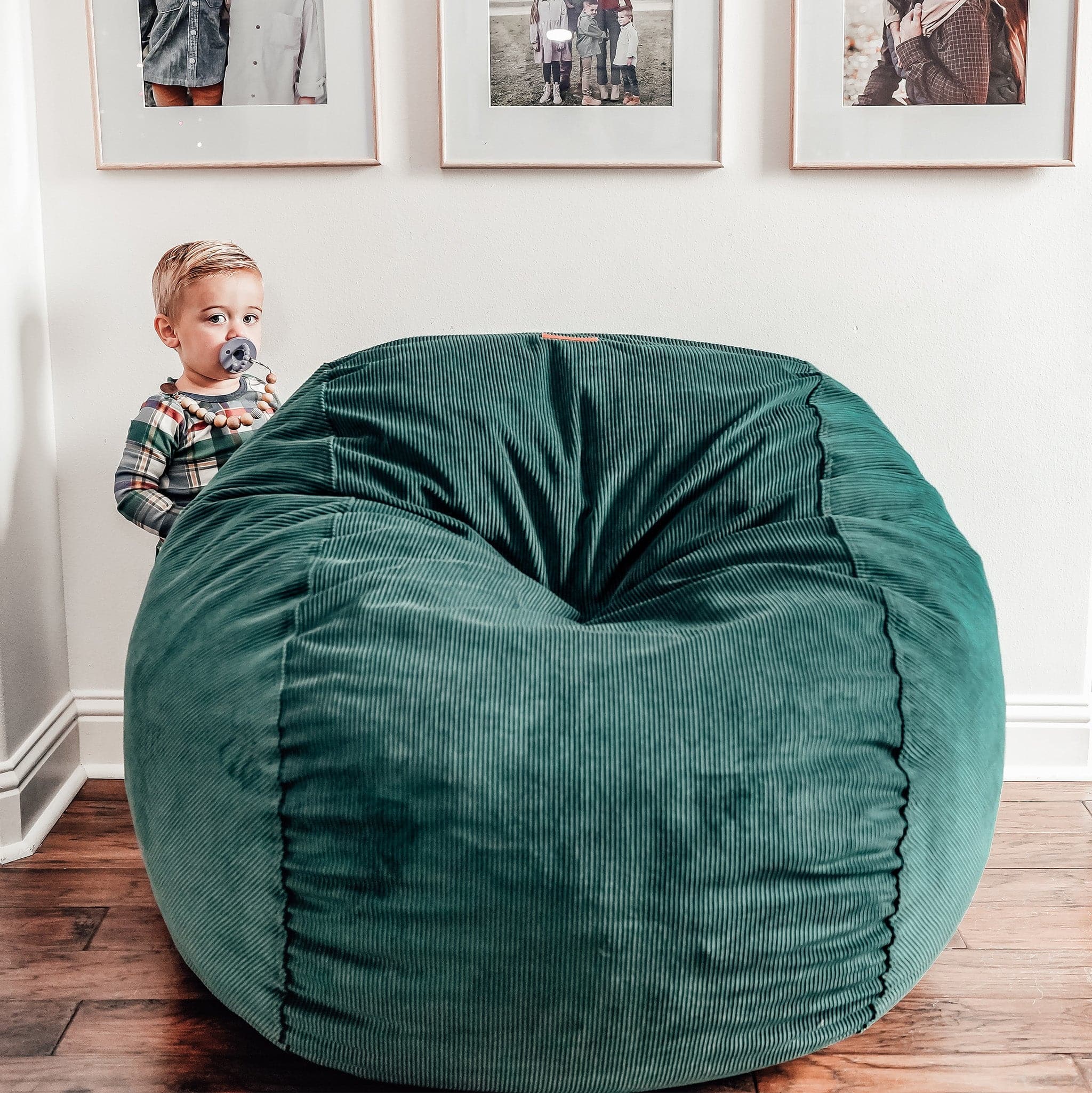 A child stands next to a full-sized-cordaroys bean bag chair in rainforest corduroy. 