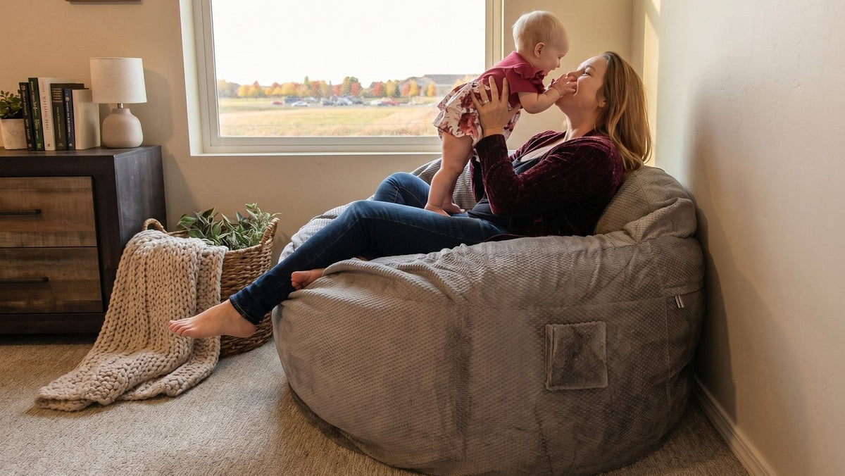 Woman sitting on a bean bag chair holding a baby in a cozy living room.