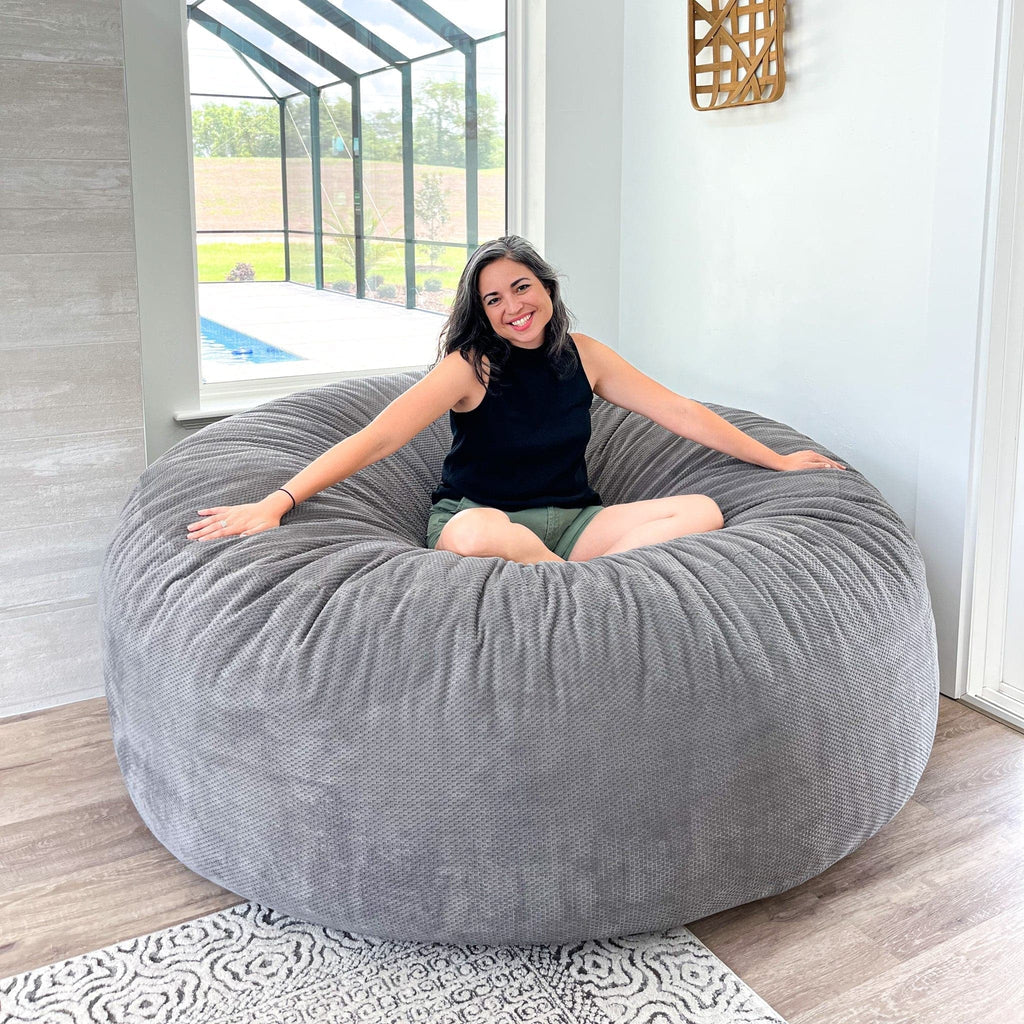 A woman sits in a chenille giant bean bag by cordaroys. 