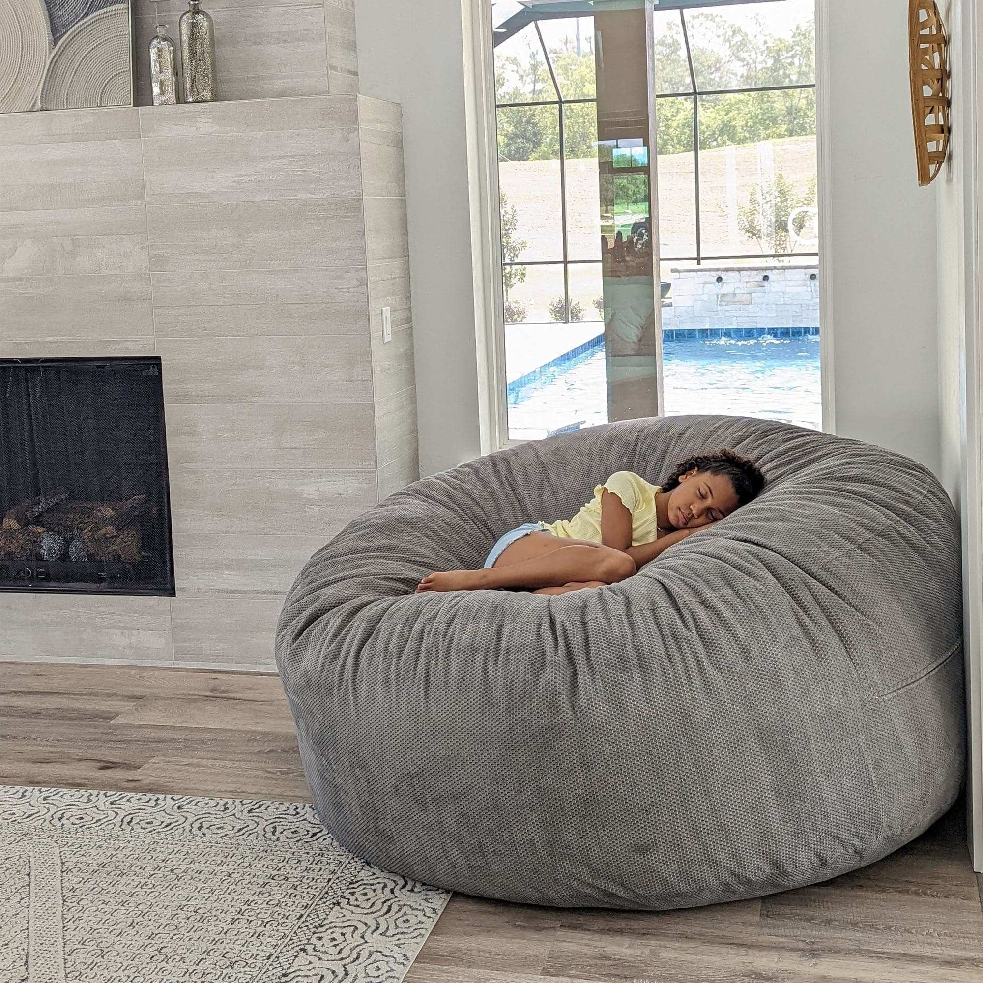 A girl sleeps in a giant chenille bean bag by cordaroys. 