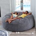 Two girls lounge in a cordaroys giant chenille bean bag inside. 