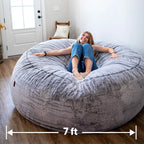 A woman sits on a cordaroys chinchilla giant bean bag chair