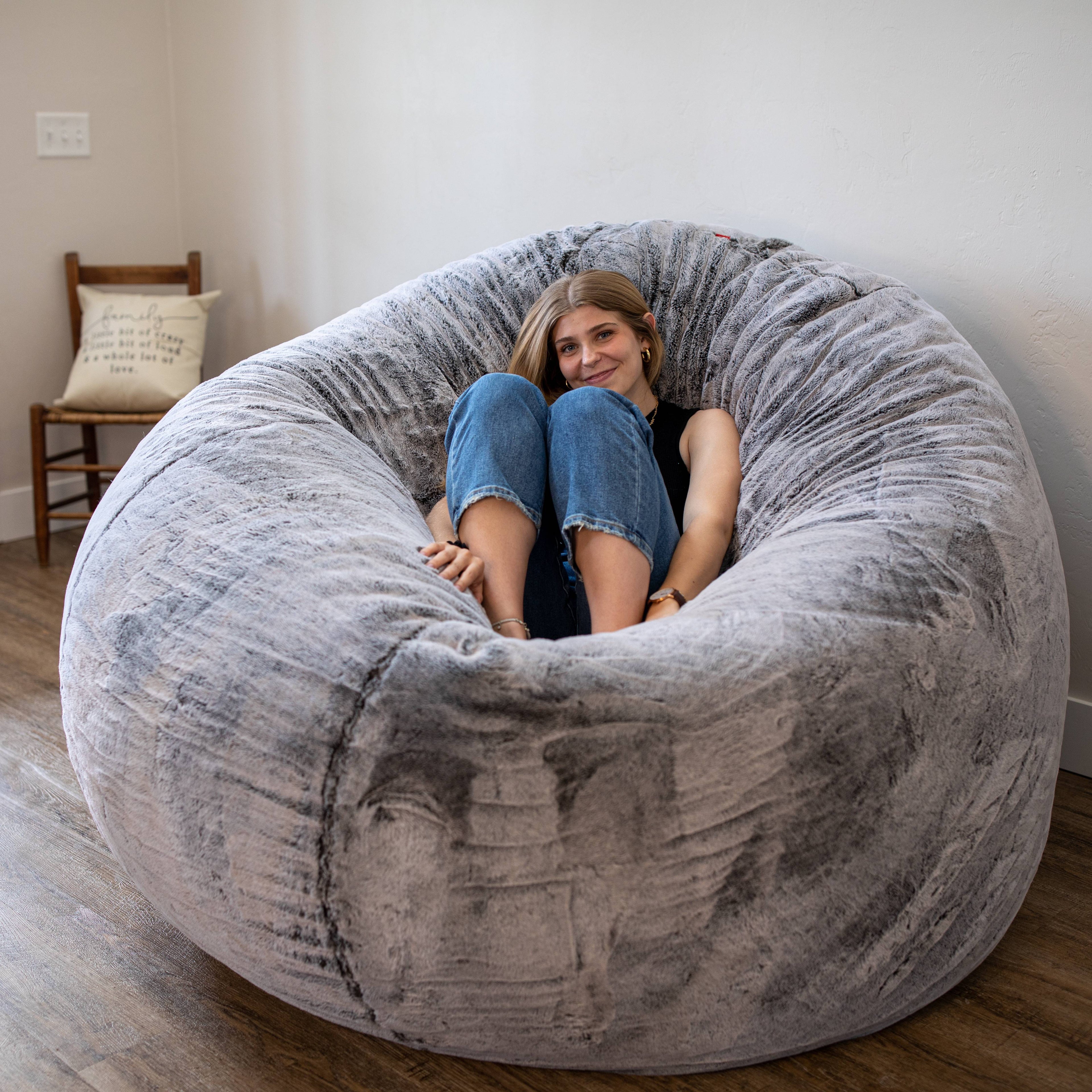 A woman sits on a chinchilla giant bean bag chair