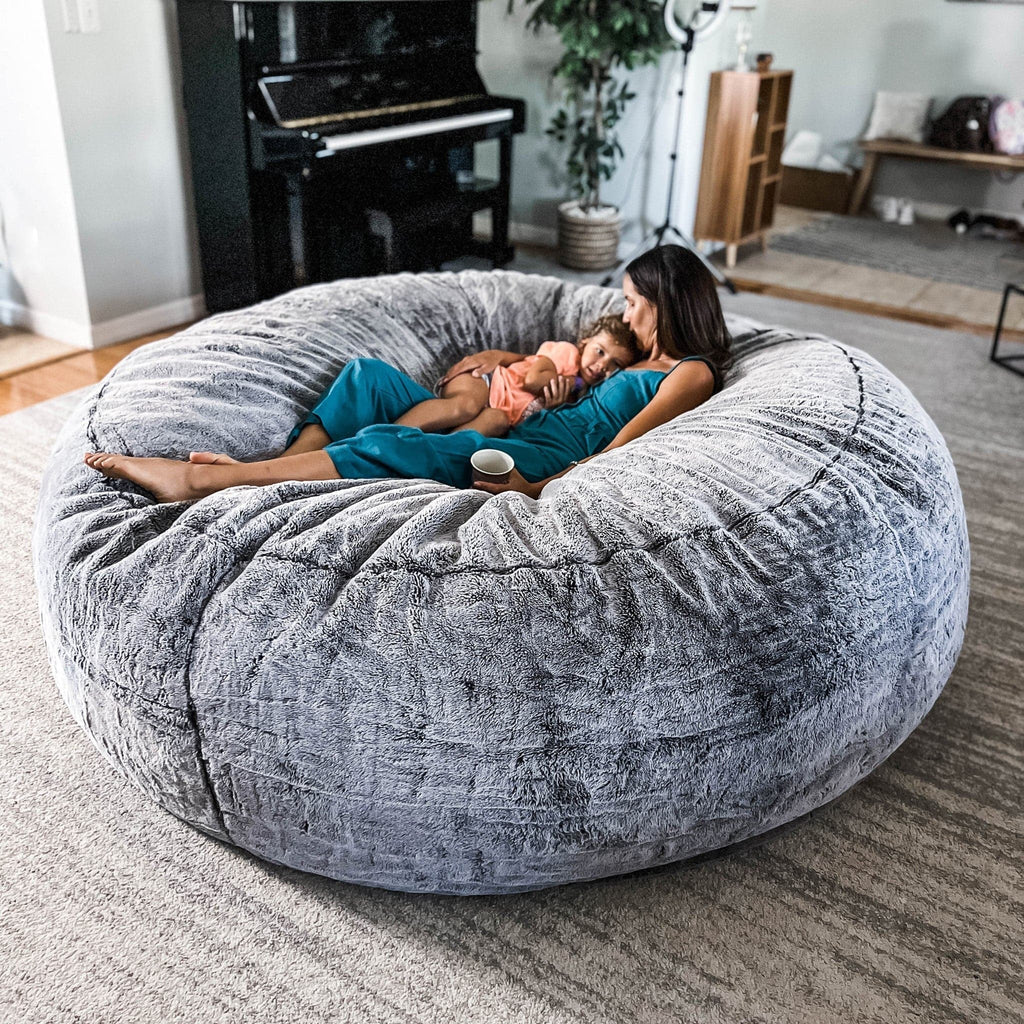 A woman cuddles her child on a chinchilla giant cordaroys bean bag chair.