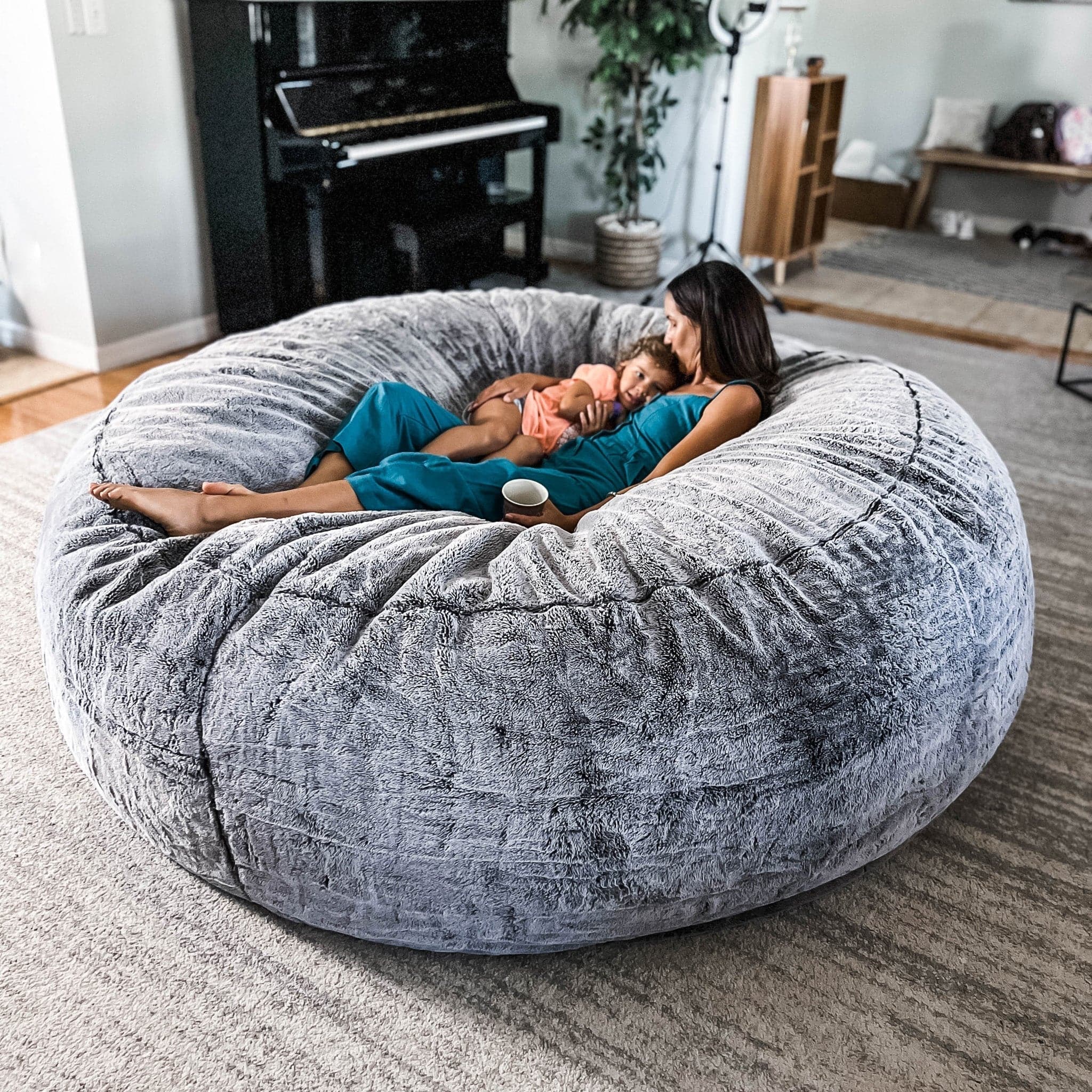 A woman cuddles her child on a chinchilla giant cordaroys bean bag chair.