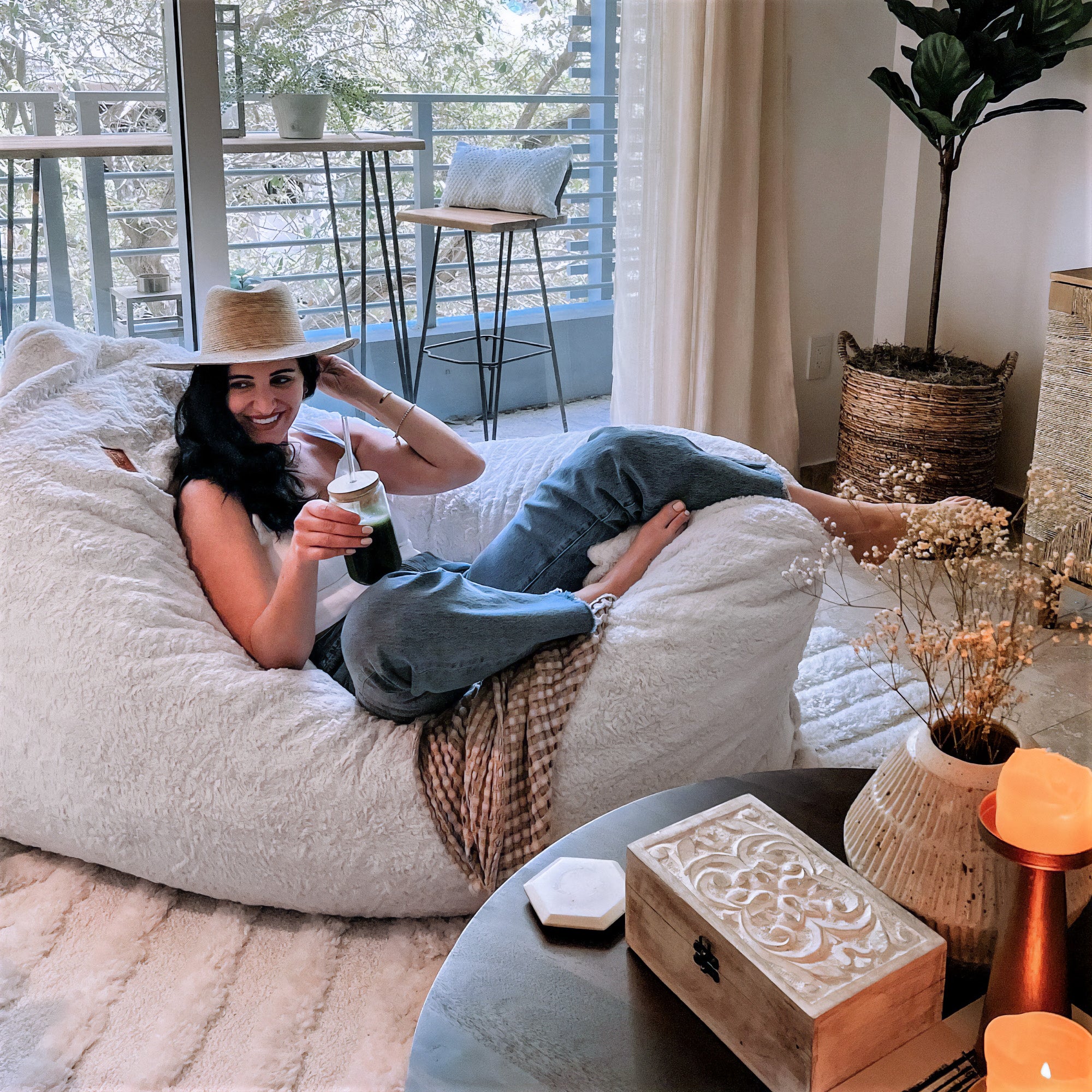 A woman sits in a cordaroys giant pillow lounger in a living room. 