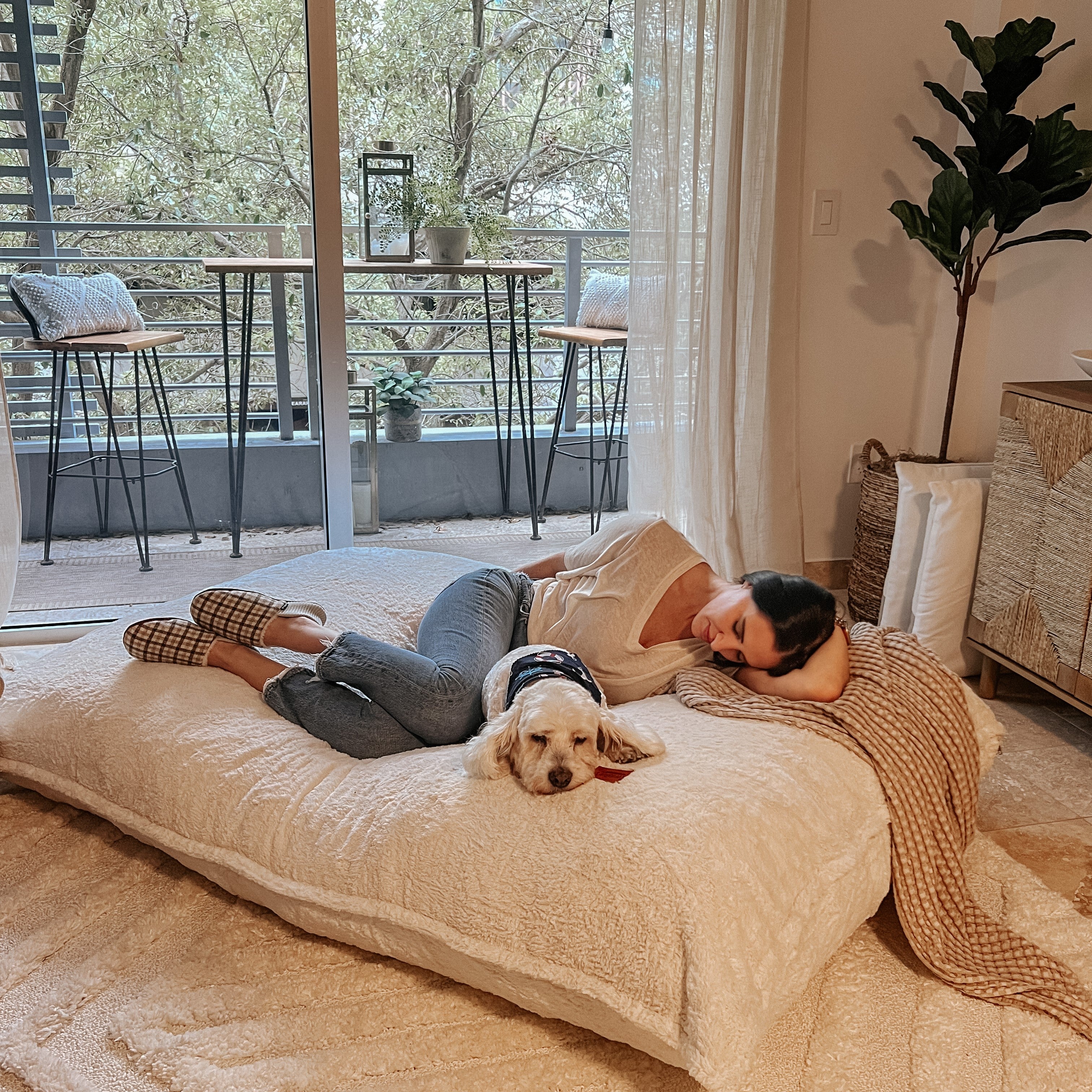 A woman and her dog lie on a flat cordaroys pillow lounger.