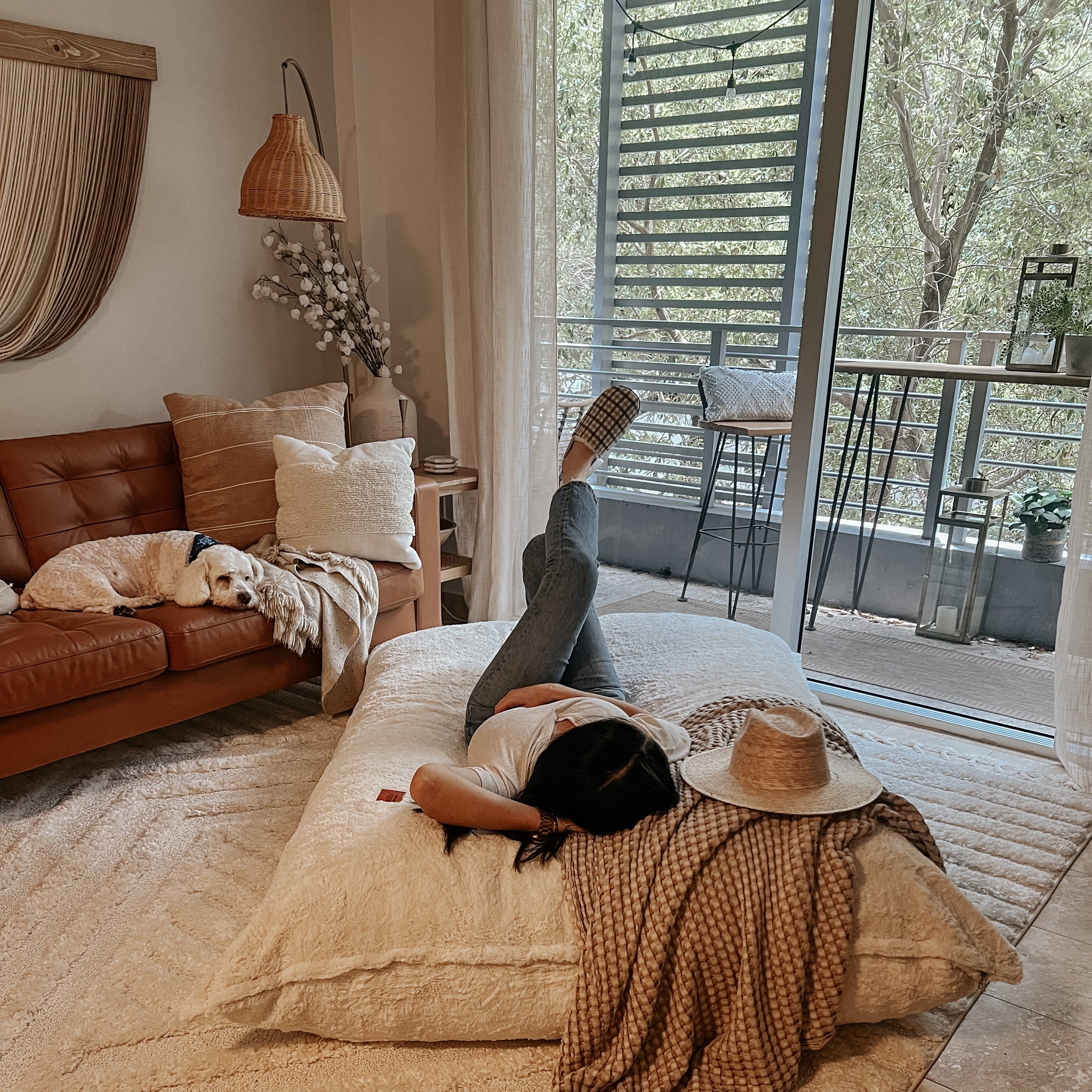 A woman lies down on a cordaroys pillow longer in a living room. 