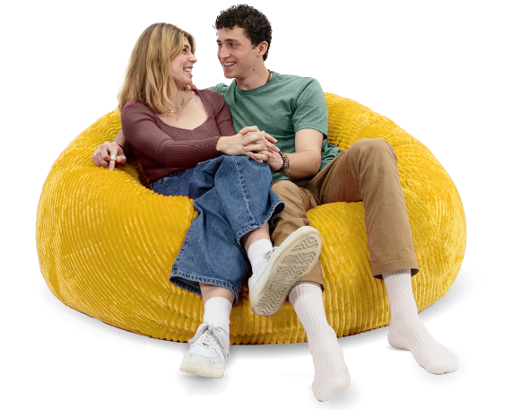 Two people sitting on a yellow bean bag chair against a white background