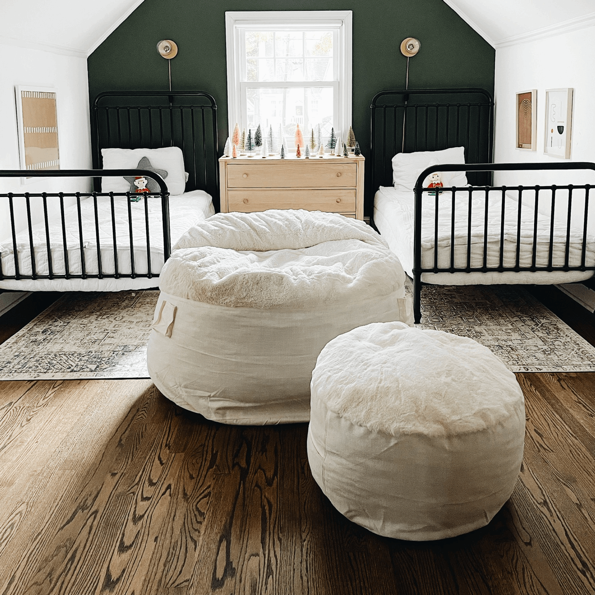 A cordaroys NEST bean bag and footstool are between two beds in a guest room.